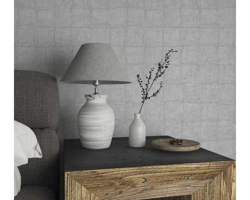 Nature morte décorative avec lampe, vase et bol en bois sur une table de chevet devant un mur texturé