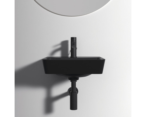 Schwarzes Waschbecken mit Wasserhahn und Siphon vor einer Wand