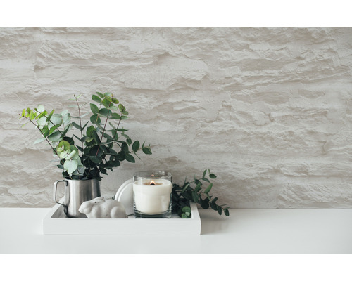Scène décorative avec bougie, eucalyptus et mur en pierre
