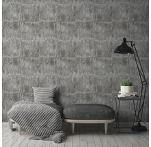 Papier peint briques grises dans un salon élégant avec lampe, tabouret et coussins.