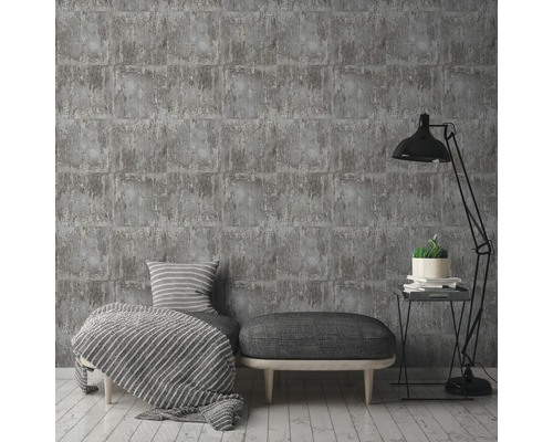 Papier peint briques grises dans un salon élégant avec lampe, tabouret et coussins.