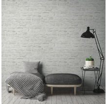 Salon avec papier peint imitation briques, fauteuil, tabouret et lampadaire.