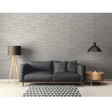 Salon avec canapé, lampadaire et suspension devant un mur structuré