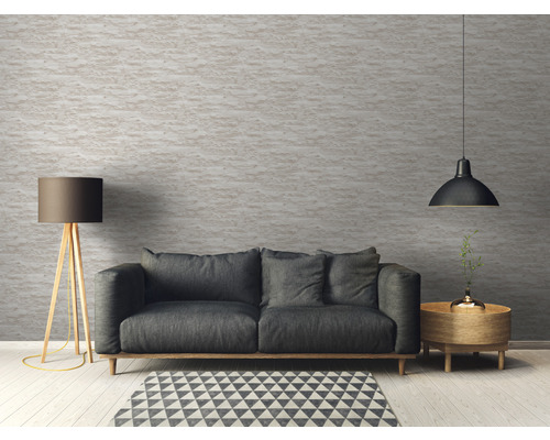 Salon avec canapé, lampadaire et suspension devant un mur structuré