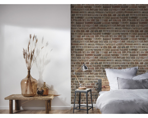 Chambre à coucher avec lit devant un mur de briques et décoration sur une table en bois