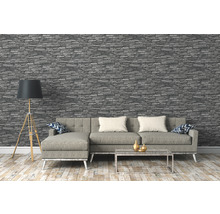 Salon avec papier peint imitation pierre grise, canapé, lampadaire et table basse.