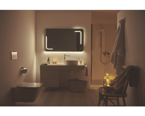 Salle de bain avec miroir lumineux, lavabo, toilettes et douche pour une ambiance lumineuse et spacieuse.