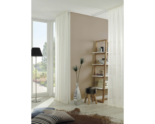 Salon lumineux avec rideaux blancs, étagère en bois et éléments décoratifs.