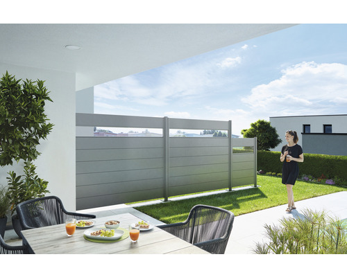 Terrasse mit Sichtschutzzaun, Tisch und Stühlen im Garten.