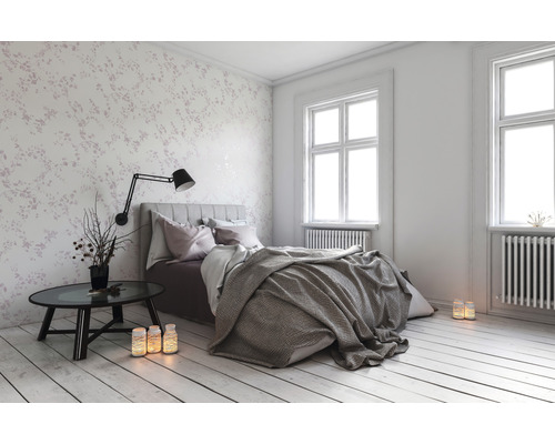 Schlafzimmer mit Bett, Nachttisch und floraler Tapete