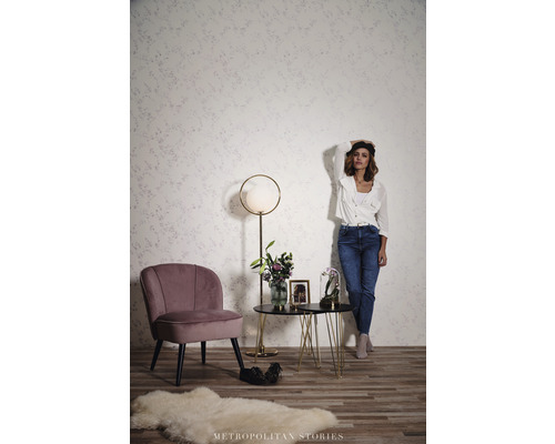 Wohnzimmer mit Sessel, Beistelltisch und Stehlampe vor einer gemusterten Wand