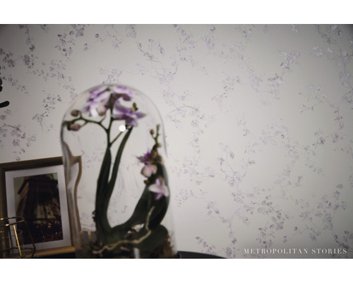 Nahaufnahme einer Wand mit Blumentapete und einer Orchidee unter einer Glaskuppel.