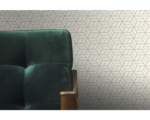 Detailansicht einer geometrischen Tapete mit einem grünen Sessel im Vordergrund.