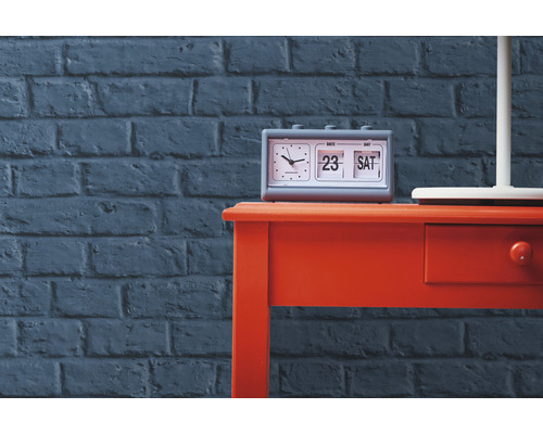 Table avec réveil à affichage à palettes devant un mur de briques