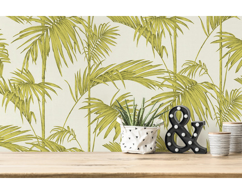 Ambiance de pièce avec papier peint à motif de palmiers, plante et signe & décoratif sur une table en bois.