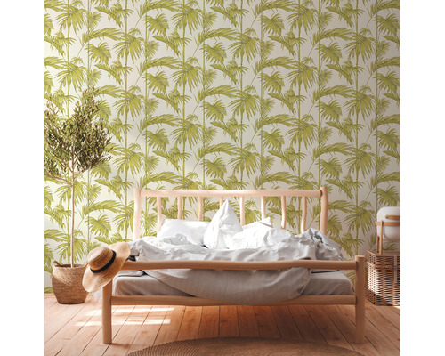 Une chambre avec un lit et du papier peint à motifs de feuilles.