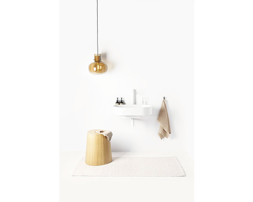 Salle de bain avec tabouret, lavabo, serviette, lampe et tapis de bain