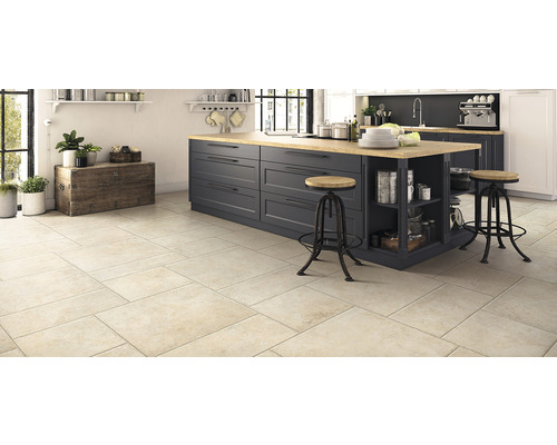 Cuisine claire avec carrelage, îlot de cuisine et tabourets de bar.