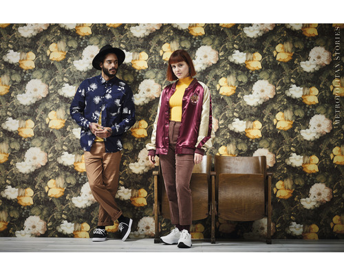 Deux personnes posent devant un mur avec un décor floral