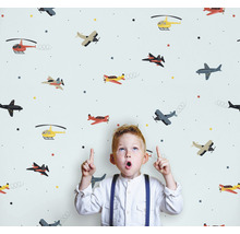 Kind vor einer Tapete mit Flugzeugmuster