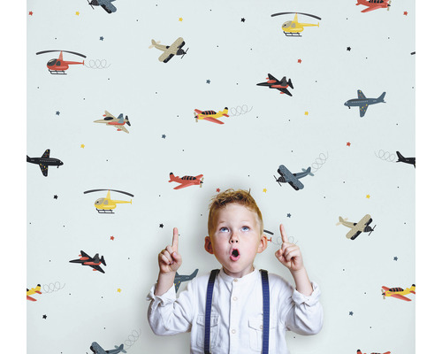 Kind vor einer Tapete mit Flugzeugmuster