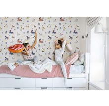 Deux filles sont assises sur un lit devant un mur à motif de licorne.