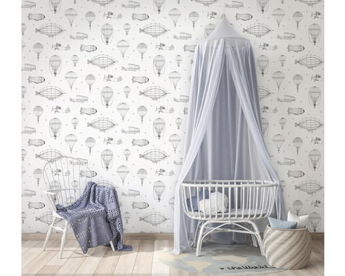 Chambre avec papier peint sur le thème de l''aviation, lit de bébé avec baldaquin et chaise avec couverture