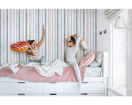 Chambre de fille avec papier peint rayé, lit et tiroirs