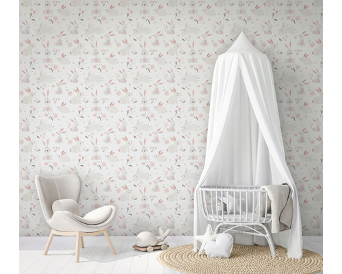 Chambre d''enfant avec papier peint à motifs de lapins, fauteuil et lit de bébé avec baldaquin.