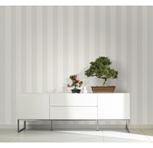 Raumansicht mit gestreifter Tapete, weissem Sideboard und Bonsai-Pflanzen als Dekoration