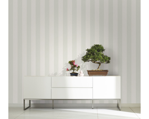 Raumansicht mit gestreifter Tapete, weissem Sideboard und Bonsai-Pflanzen als Dekoration