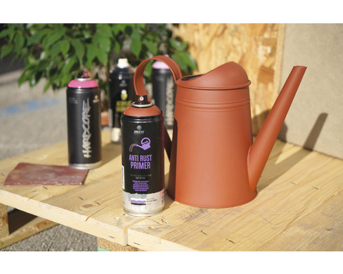 Peinture en aérosol, apprêt antirouille et arrosoir sur une table en bois