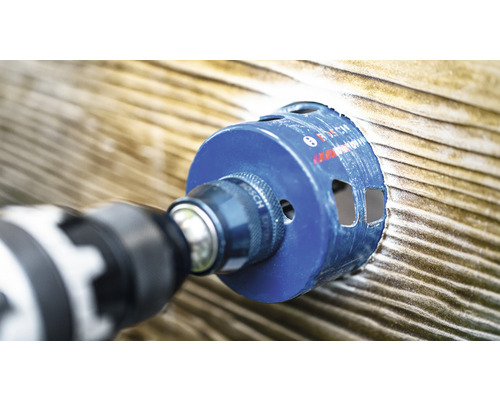 Perceuse avec scie cloche perçant une planche de bois