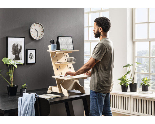 Bureau debout en bois avec une personne travaillant dessus dans une pièce lumineuse.
