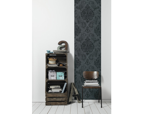Dekoratives Interieur mit Regal aus Holzkisten, Stuhl und gemusterter Tapete