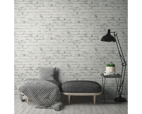 Dekoratives Wohnambiente mit Ziegelmuster-Tapete, Sitzgelegenheit, Stehlampe und Beistelltisch.