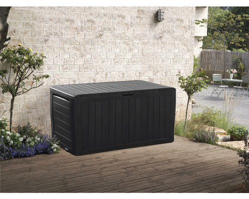 Schwarze Gartenbox auf einer Terrasse vor einer Ziegelwand