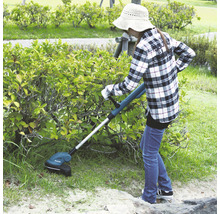 Une femme coupe l''herbe avec un coupe-bordures à batterie dans le jardin.