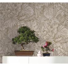 Deux bonsaïs sur une armoire devant un mur avec du papier peint à motifs de feuilles.