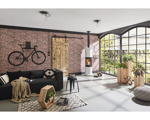 Wohnzimmer mit Sofa, Kaminofen, Schiebetür, Fenster und dekorativen Elementen für eine gemütliche Atmosphäre.