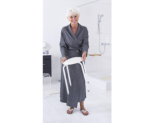 Frau hält Duschhocker im Badezimmer mit weißen Fliesen