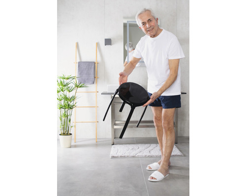 Heller Raum mit Mann, Waschbecken und schwarzem Hocker