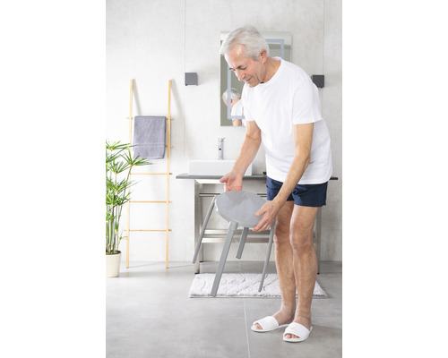 Modernes Badezimmer mit grauer Sitzgelegenheit, Waschtisch und Dekoleiter.