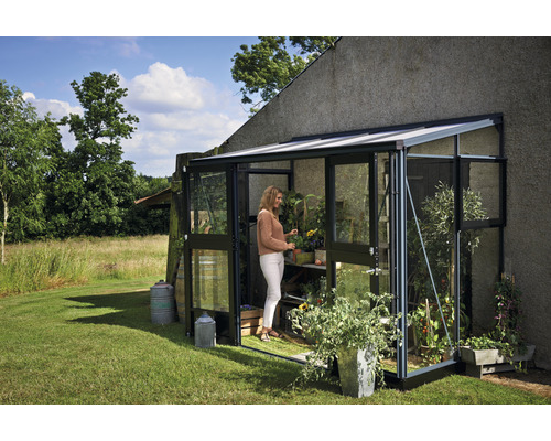 Gewächshaus mit Pflanzen und einer Frau im Garten.