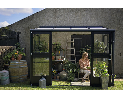 Gewächshaus im Garten mit Frau auf einem Stuhl
