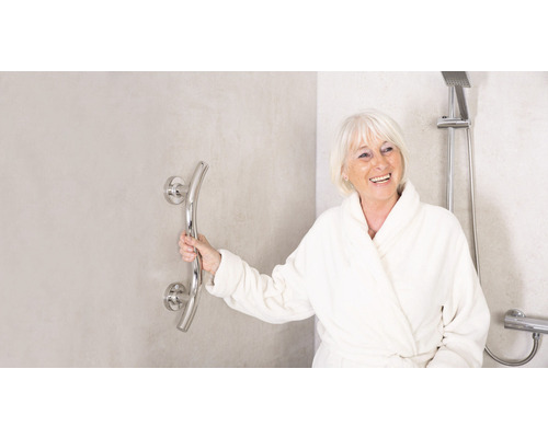 Frau im Bademantel hält einen Haltegriff an der Wand neben einer Dusche.