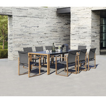 Scène de jardin avec table à manger et chaises d''extérieur devant un mur en pierre.