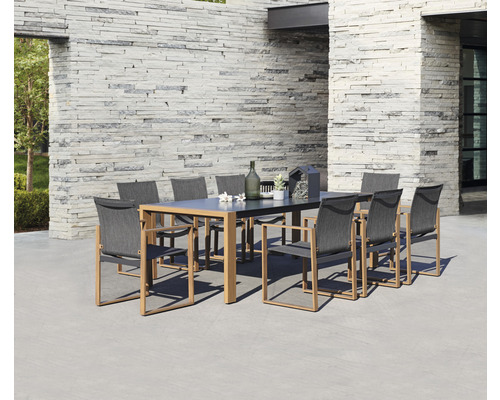 Scène de jardin avec table à manger et chaises d''extérieur devant un mur en pierre.