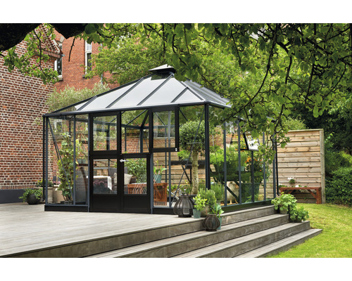 Gewächshaus mit Glaswänden und dunklem Rahmen auf einer Holzterrasse im Garten.