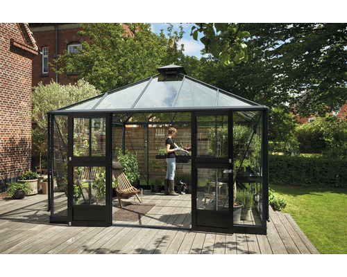 Gewächshaus mit Glas, Tür und Holzterrasse im Garten.